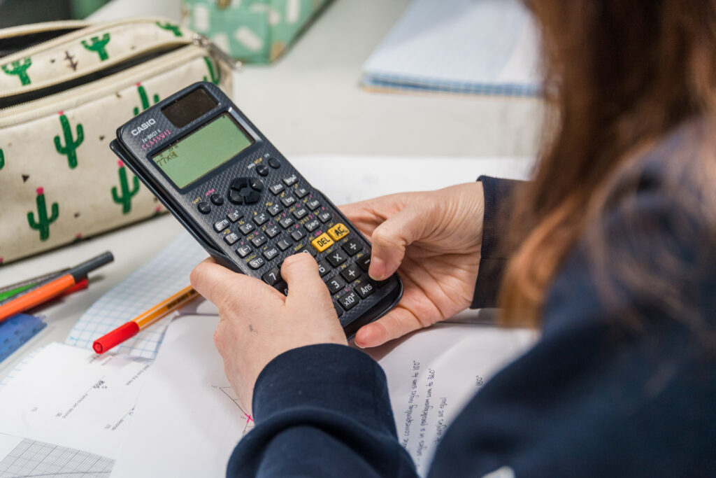 A female student holding and using a scientific calculator in a Math class